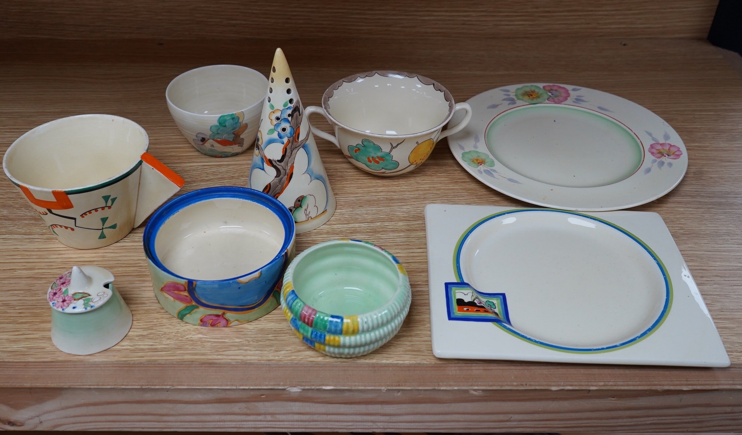 A collection of Clarice Cliff including; a Tiger Tree conical sugar sifter (c.1937), a cup marked 5799, a two handled pomegranate cup, a bowl, two plates, a mustard pot, etc. Condition - fair